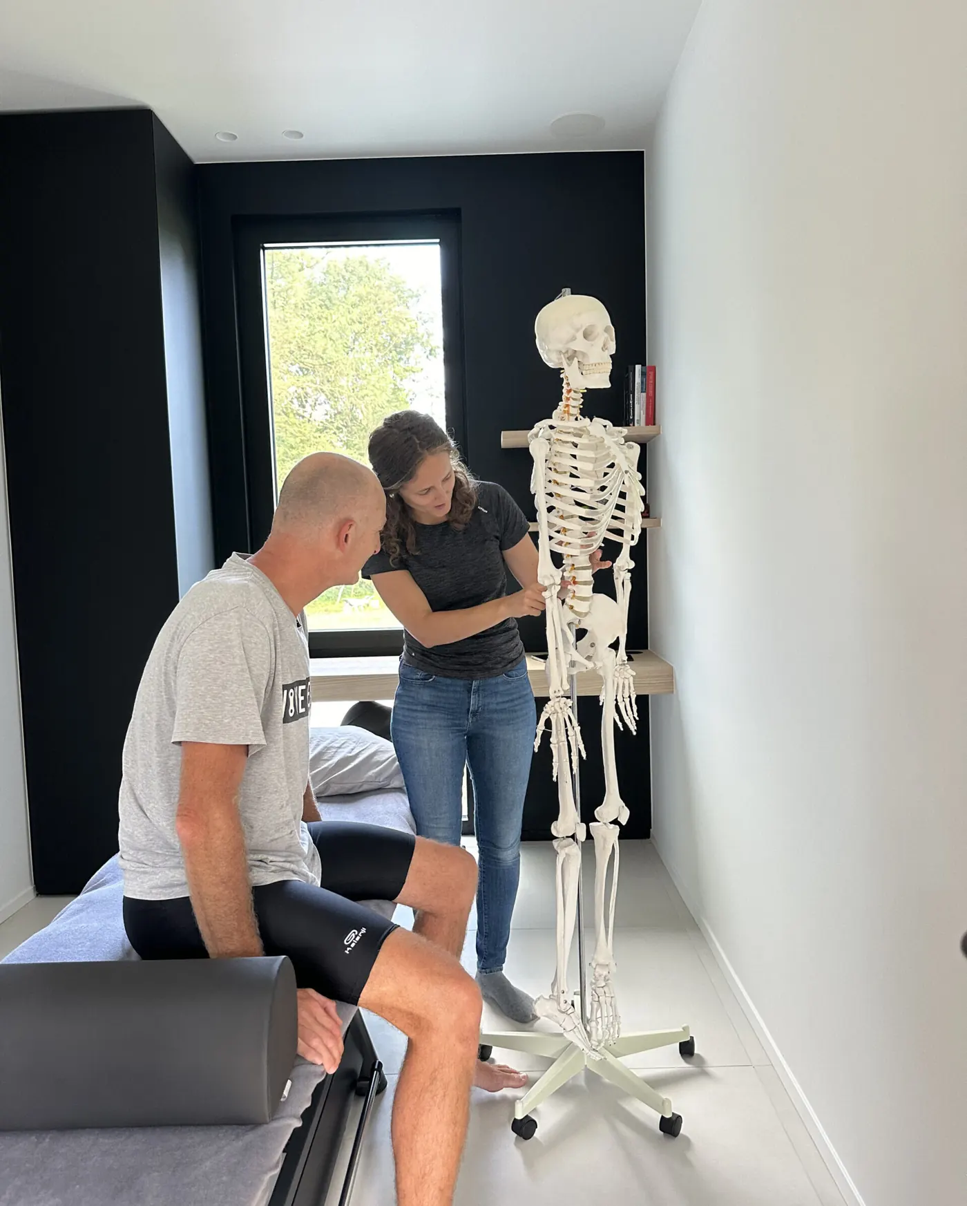 Kinesitherapeut legt een oefening uit aan een patiënt in de praktijk